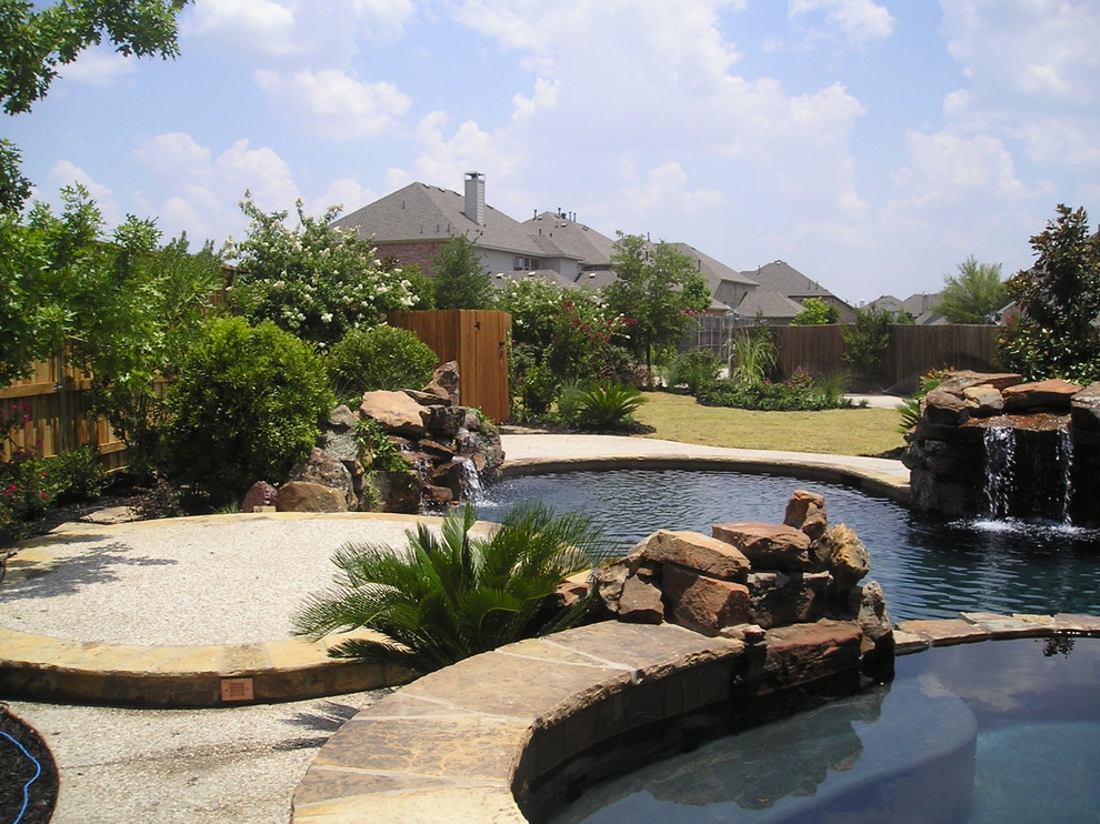 Diseño de piscinas y jacuzzis naturales de estilo americano grandes a medida en patio trasero con losas de hormigón