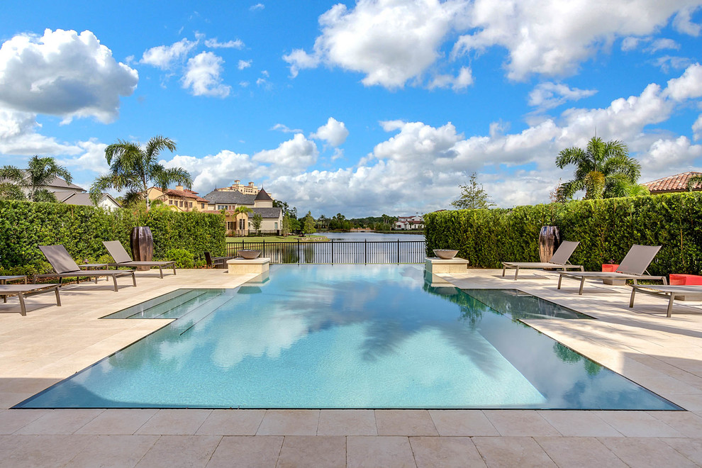 Large contemporary back rectangular infinity swimming pool in Orlando with tiled flooring.