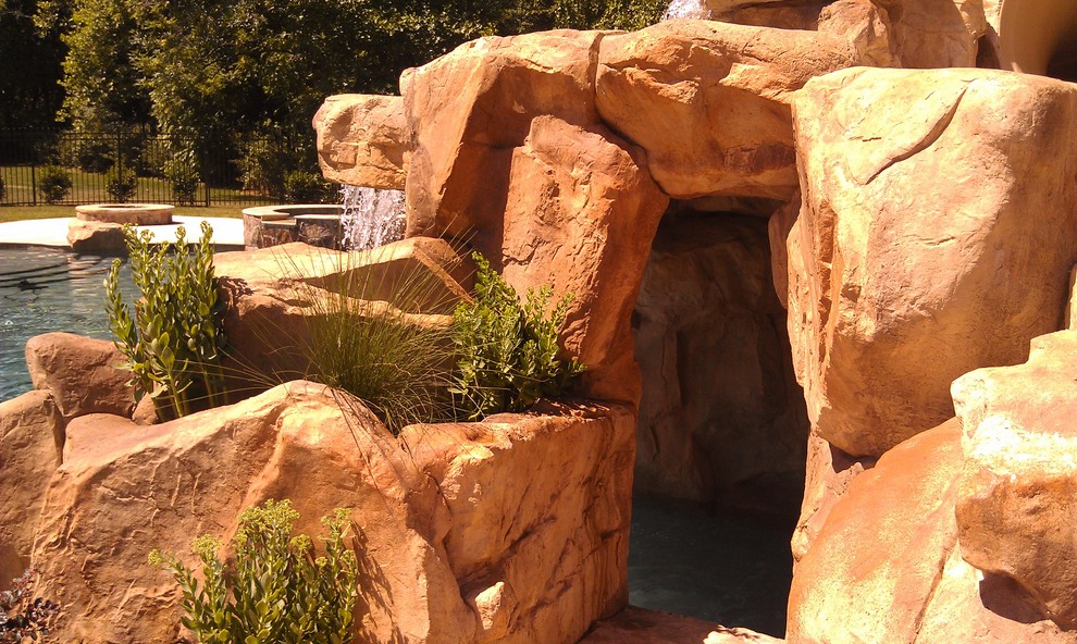 Foto de piscina con fuente tropical grande a medida en patio trasero con adoquines de piedra natural