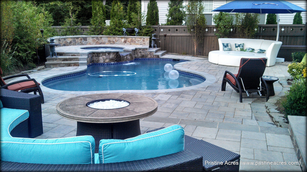 Foto di un'ampia piscina naturale tradizionale personalizzata dietro casa con fontane e pavimentazioni in cemento
