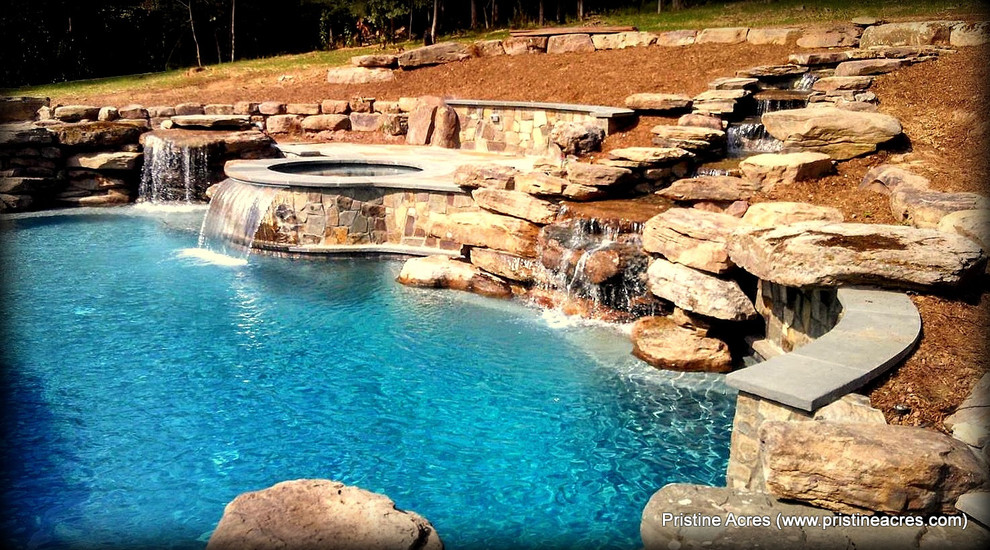 Immagine di un'ampia piscina naturale chic personalizzata dietro casa con fontane e pavimentazioni in cemento