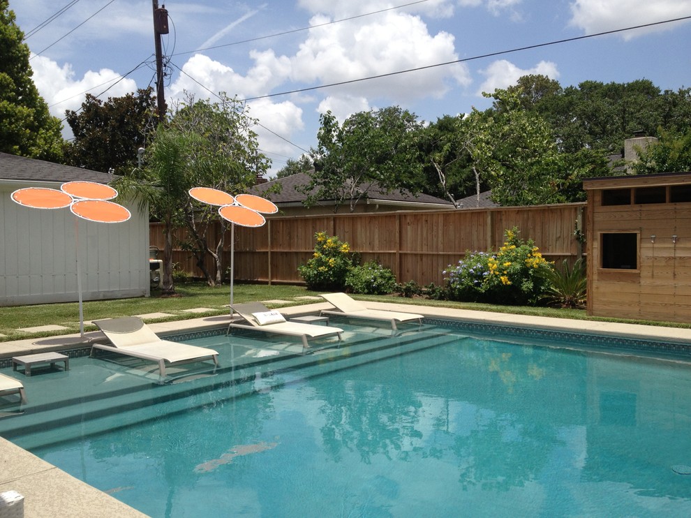 Modelo de piscina clásica pequeña rectangular en patio trasero con losas de hormigón