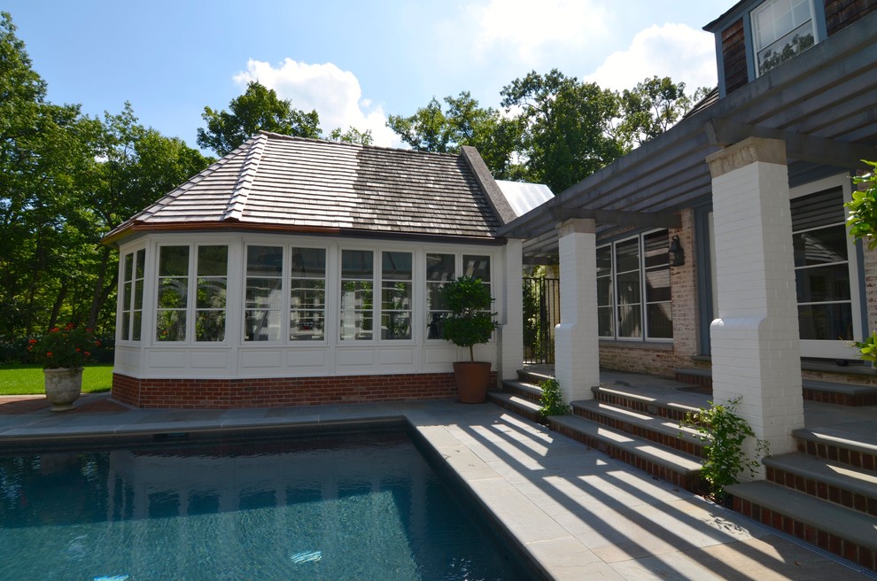 Modelo de casa de la piscina y piscina alargada tradicional grande rectangular en patio trasero con adoquines de ladrillo