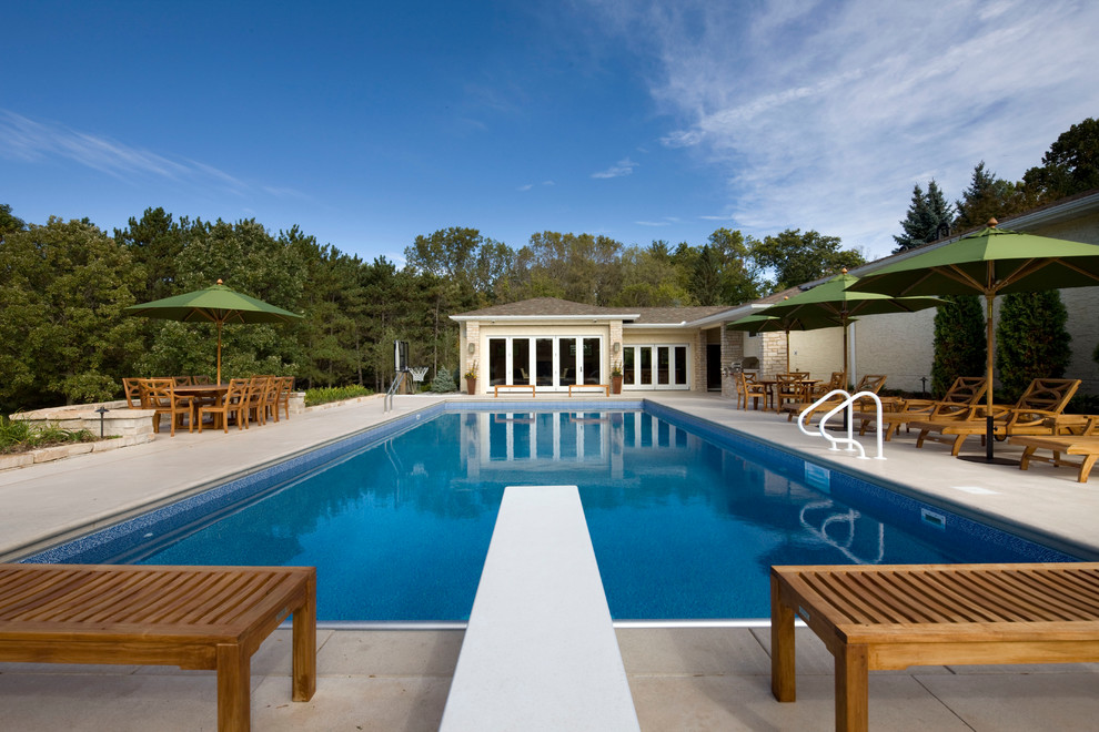 Diseño de piscina natural contemporánea grande rectangular en patio trasero con losas de hormigón