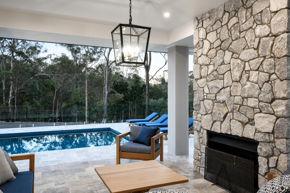 Ejemplo de casa de la piscina y piscina clásica de tamaño medio rectangular en patio trasero con adoquines de piedra natural