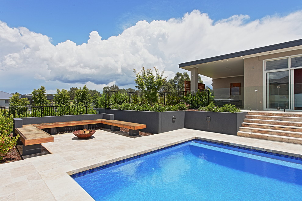 Exempel på en mycket stor modern rektangulär pool på baksidan av huset, med poolhus och naturstensplattor