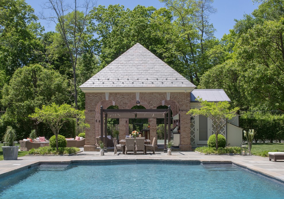 Idee per un'ampia piscina monocorsia chic rettangolare dietro casa con pavimentazioni in pietra naturale