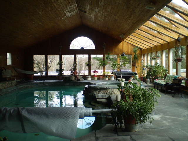 Foto på en stor lantlig pool, med poolhus och naturstensplattor