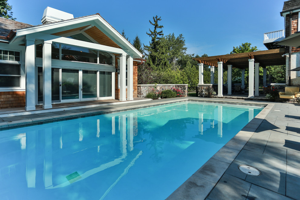 Modelo de casa de la piscina y piscina natural tradicional renovada grande rectangular en patio lateral con adoquines de piedra natural