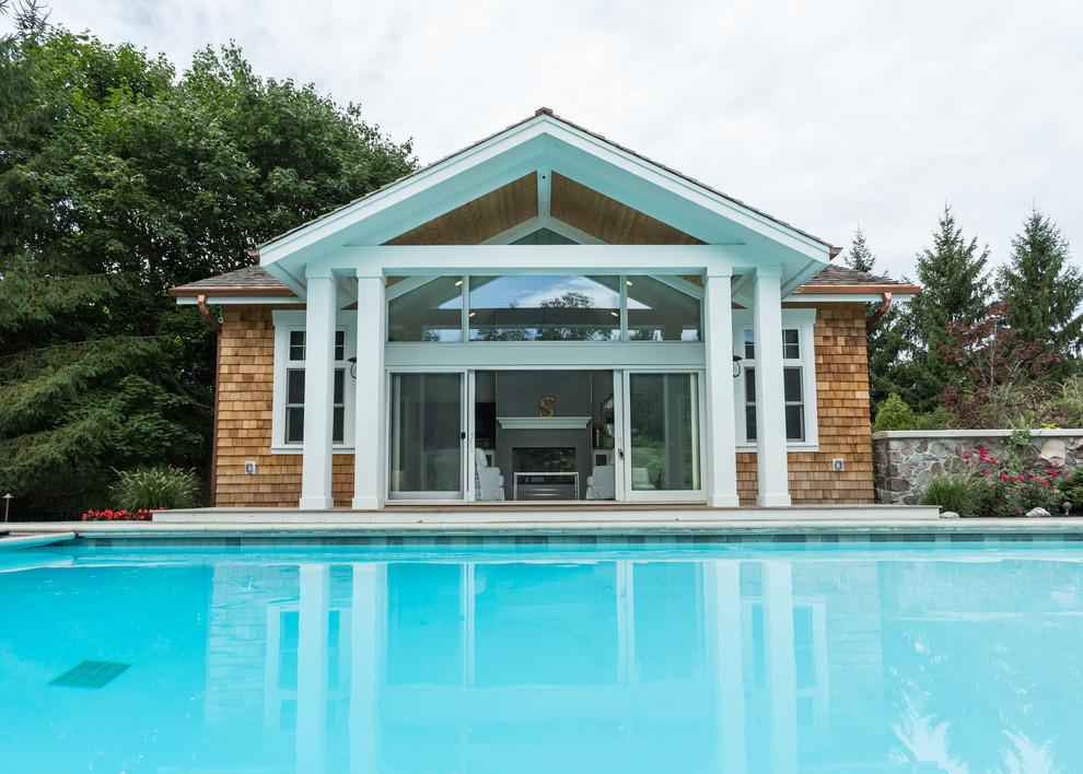 Ejemplo de casa de la piscina y piscina natural tradicional renovada grande rectangular en patio lateral con adoquines de piedra natural