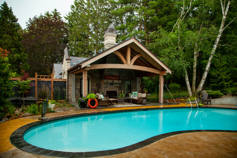 Идея дизайна: спортивный бассейн среднего размера, в форме фасоли на заднем дворе в стиле фьюжн с домиком у бассейна и покрытием из декоративного бетона