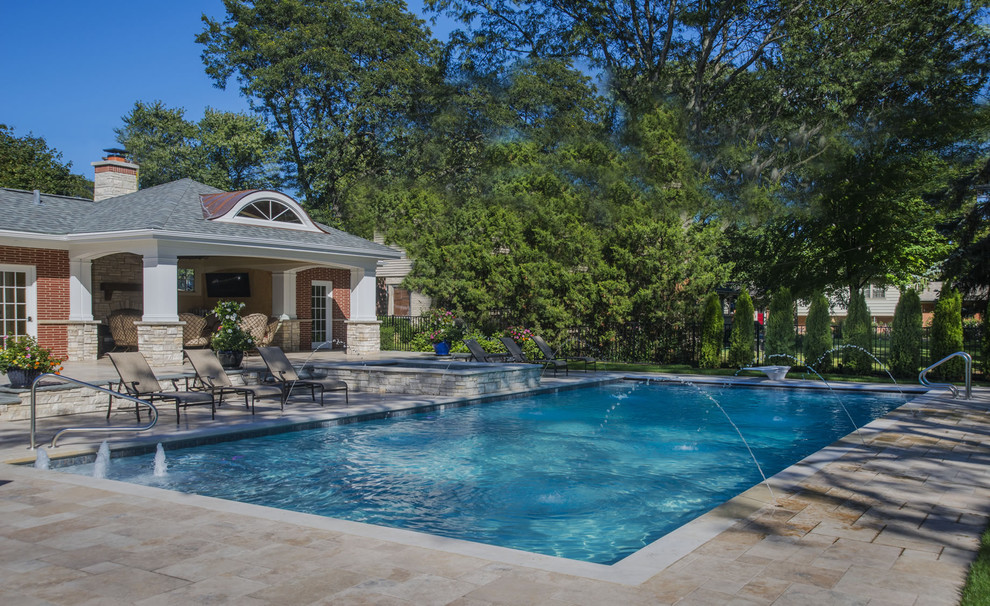 Ejemplo de casa de la piscina y piscina tradicional de tamaño medio rectangular en patio trasero con adoquines de piedra natural