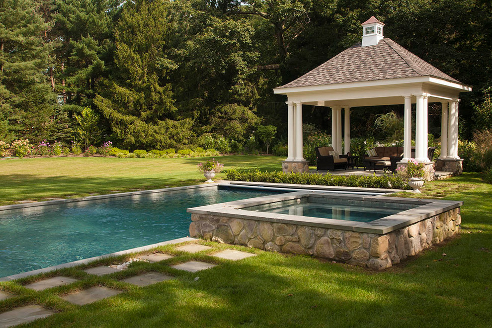 На фото: спортивный, прямоугольный бассейн среднего размера на заднем дворе в классическом стиле с джакузи и покрытием из каменной брусчатки