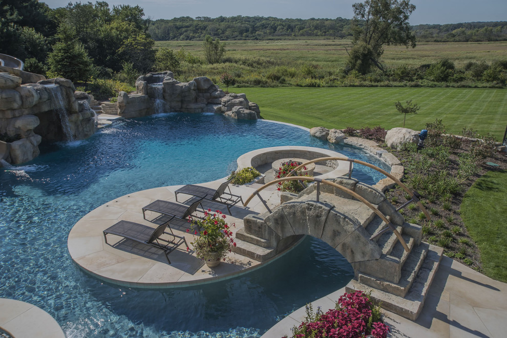 Ejemplo de piscina con fuente infinita extra grande a medida en patio trasero con adoquines de piedra natural