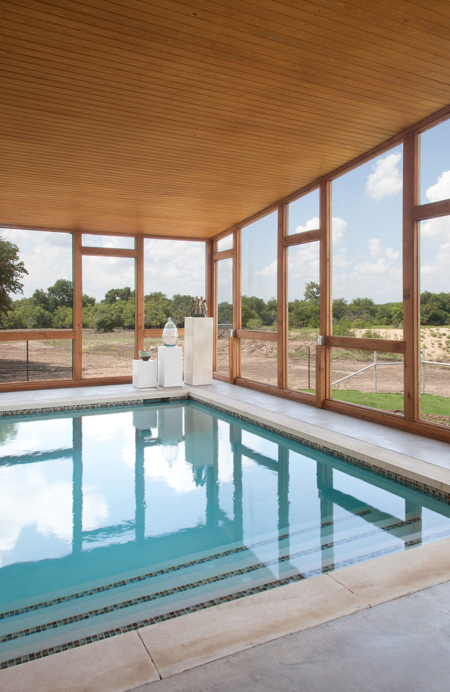 Cette photo montre une grande piscine intérieure moderne rectangle avec une dalle de béton.