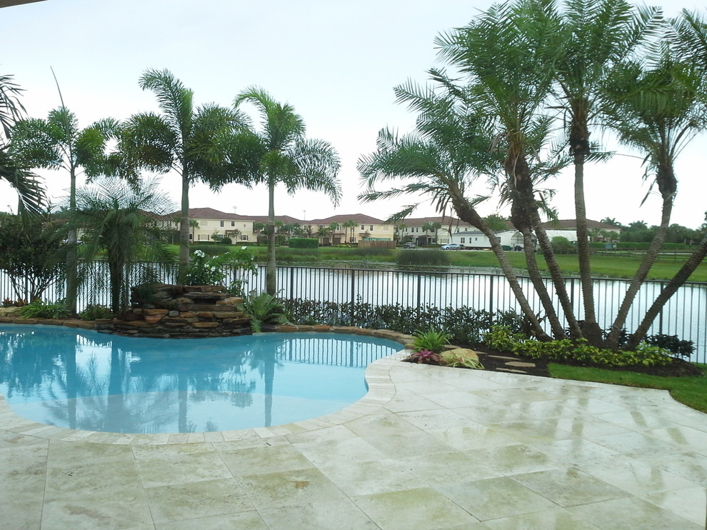 Foto de piscina con tobogán natural tropical grande rectangular en patio trasero con adoquines de piedra natural