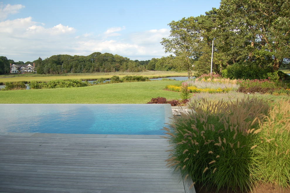 Diseño de piscina infinita tradicional renovada de tamaño medio rectangular en patio trasero con entablado