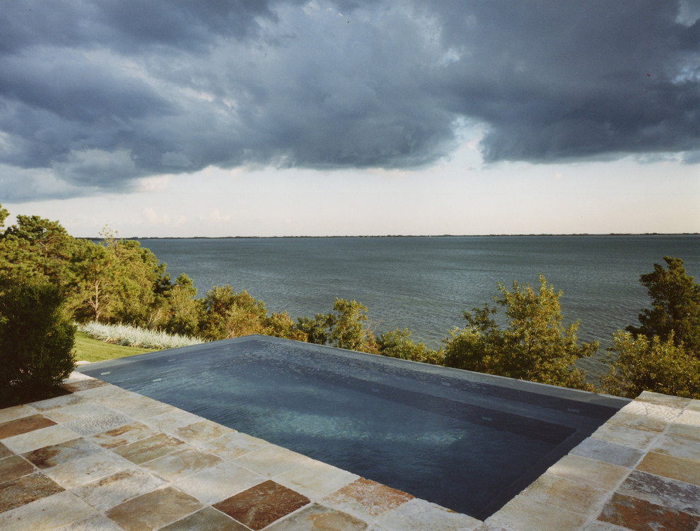 Foto de piscina infinita actual de tamaño medio rectangular en patio trasero con adoquines de piedra natural