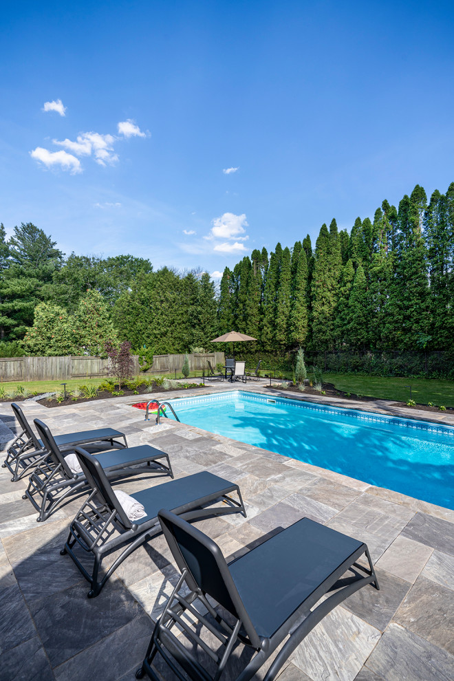 Ejemplo de piscina tradicional renovada de tamaño medio rectangular en patio trasero con paisajismo de piscina y adoquines de piedra natural