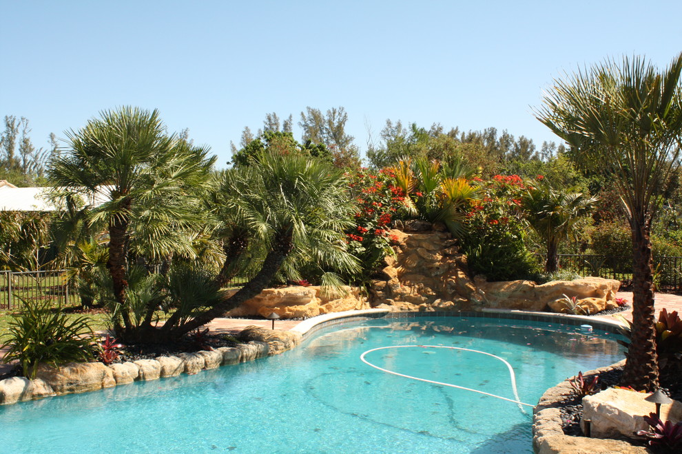 Ispirazione per una grande piscina monocorsia tropicale personalizzata dietro casa con fontane e pavimentazioni in mattoni