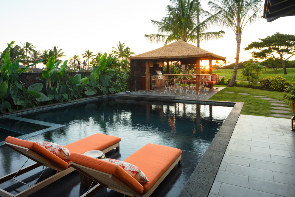 Modelo de piscina alargada exótica grande rectangular en patio trasero con suelo de baldosas