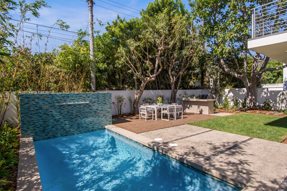 Imagen de piscina natural retro grande rectangular en patio trasero con losas de hormigón