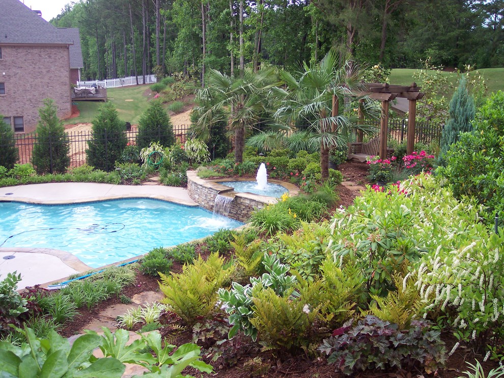Example of a mid-sized classic backyard stamped concrete and custom-shaped hot tub design in Atlanta
