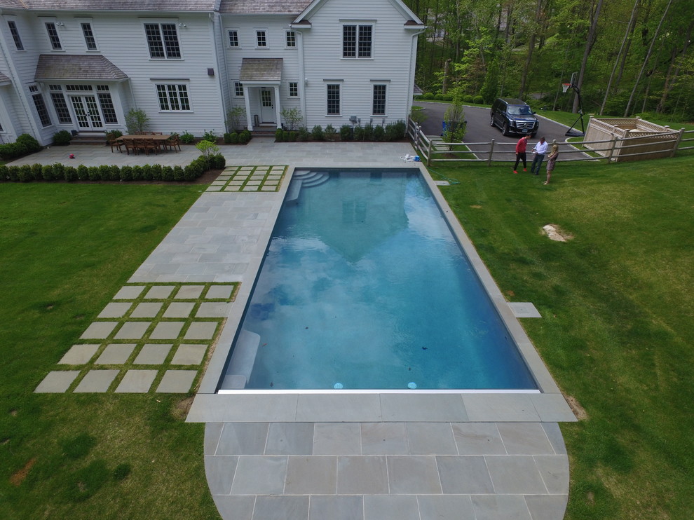 Réalisation d'une piscine arrière design de taille moyenne et rectangle avec des pavés en pierre naturelle.