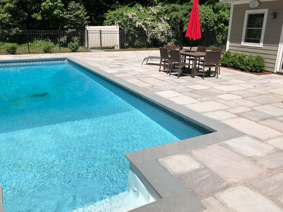Pool landscaping - contemporary backyard stone and rectangular natural pool landscaping idea in New York