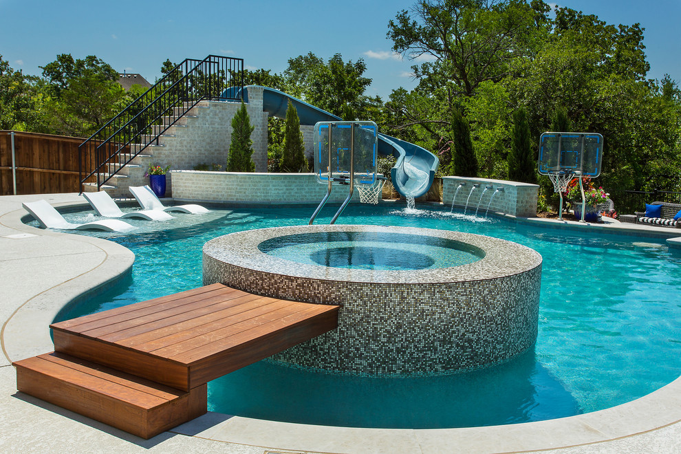 Foto de piscina con tobogán natural tradicional renovada grande a medida en patio trasero con losas de hormigón