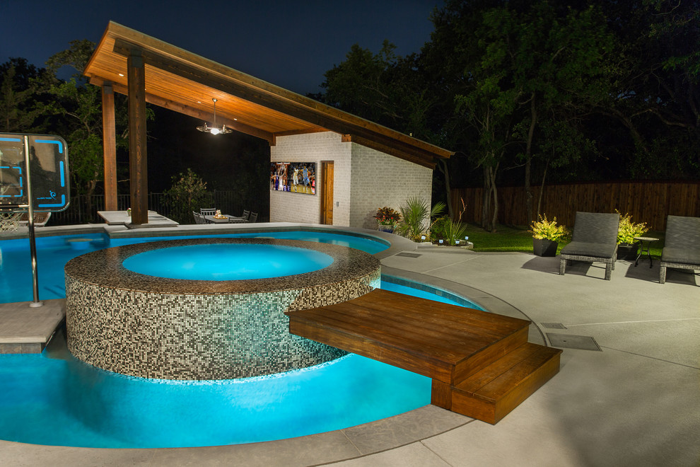 Diseño de piscina con tobogán natural clásica renovada grande a medida en patio trasero con losas de hormigón