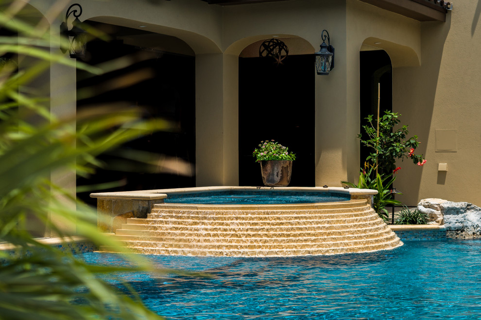 На фото: большой бассейн произвольной формы на заднем дворе в средиземноморском стиле с джакузи с