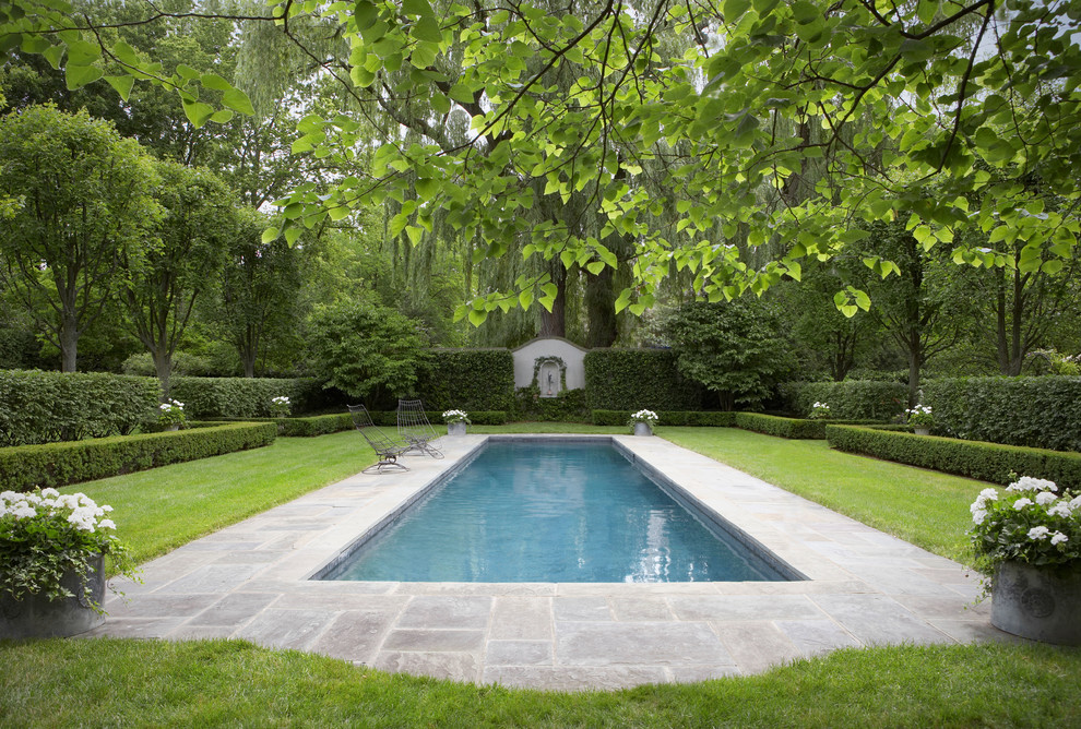 На фото: большой прямоугольный, естественный бассейн на заднем дворе в классическом стиле с покрытием из плитки с
