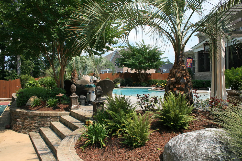 Diseño de piscina con fuente natural exótica de tamaño medio a medida en patio trasero con adoquines de piedra natural