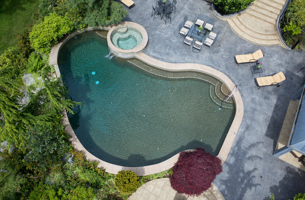 Foto di una piscina a sfioro infinito mediterranea personalizzata dietro casa con una vasca idromassaggio e cemento stampato