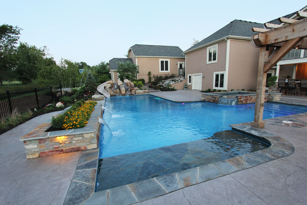 Foto de piscina con fuente natural contemporánea grande en forma de L en patio trasero con suelo de hormigón estampado
