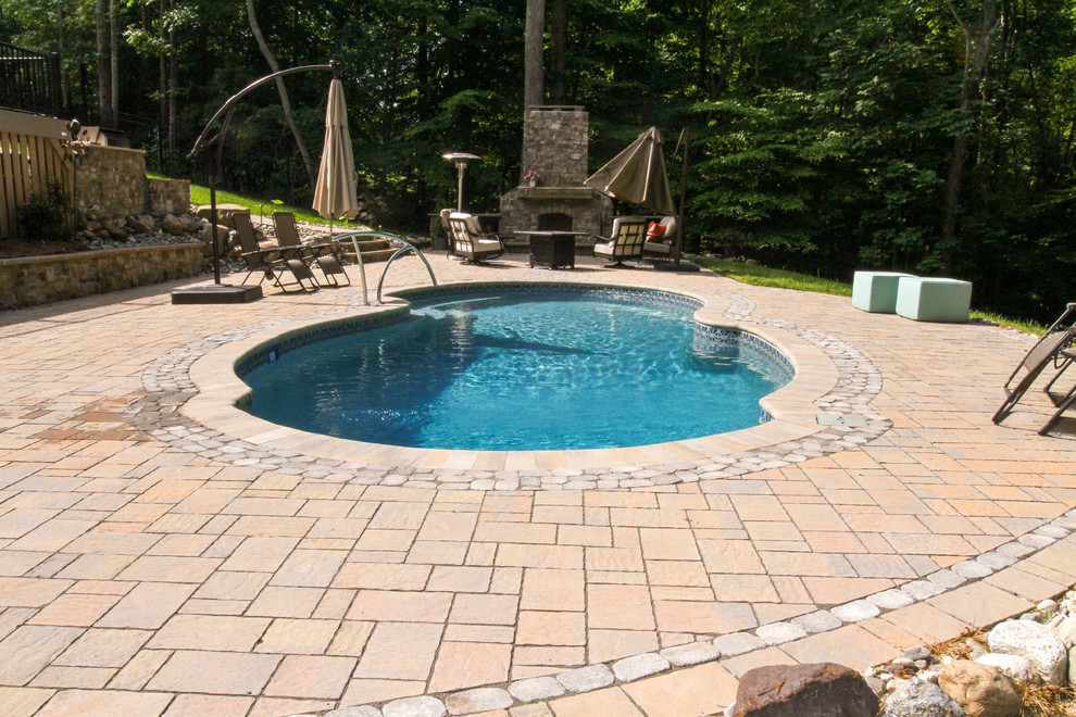 Design ideas for a large classic back custom shaped natural swimming pool in Other with natural stone paving.