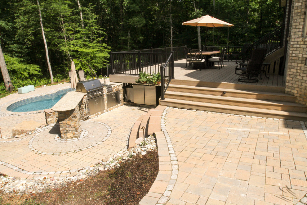 Immagine di una grande piscina naturale tradizionale personalizzata dietro casa con pavimentazioni in pietra naturale