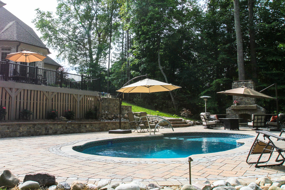 Immagine di una grande piscina naturale chic personalizzata dietro casa con pavimentazioni in pietra naturale