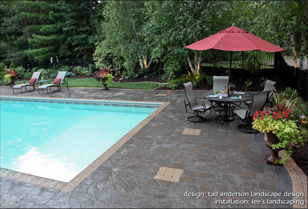 Diseño de piscina actual rectangular en patio trasero con adoquines de hormigón