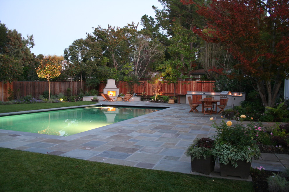 Пример оригинального дизайна: большой прямоугольный, спортивный бассейн на заднем дворе в классическом стиле с покрытием из каменной брусчатки