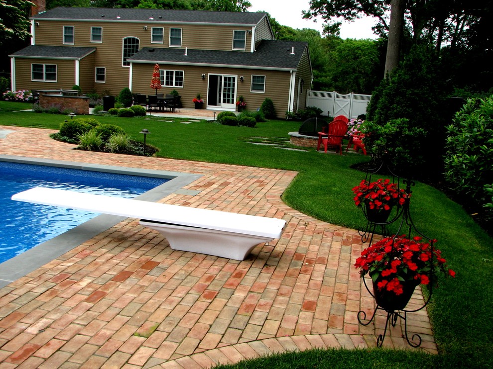 На фото: большой спортивный бассейн произвольной формы на заднем дворе в классическом стиле с покрытием из каменной брусчатки с