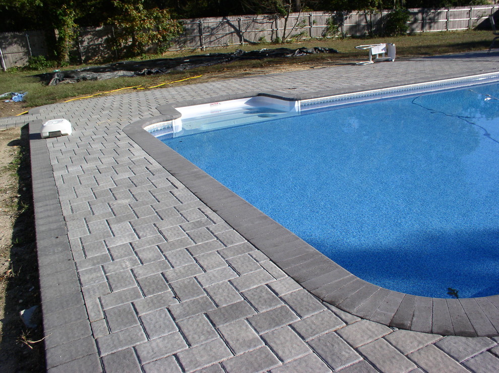 Immagine di una grande piscina monocorsia tradizionale personalizzata dietro casa con pavimentazioni in pietra naturale