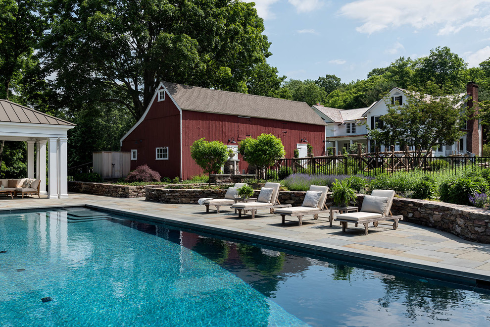 Diseño de piscina alargada clásica renovada de tamaño medio rectangular en patio trasero con adoquines de piedra natural