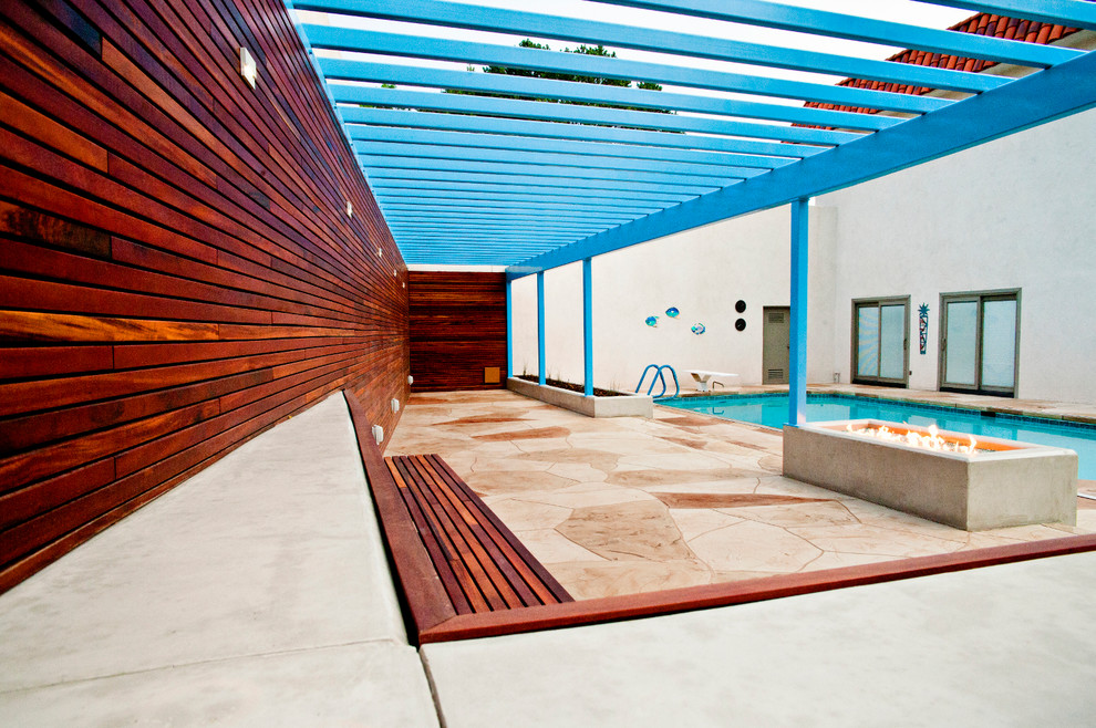 Modelo de piscina alargada actual rectangular en patio lateral con suelo de hormigón estampado