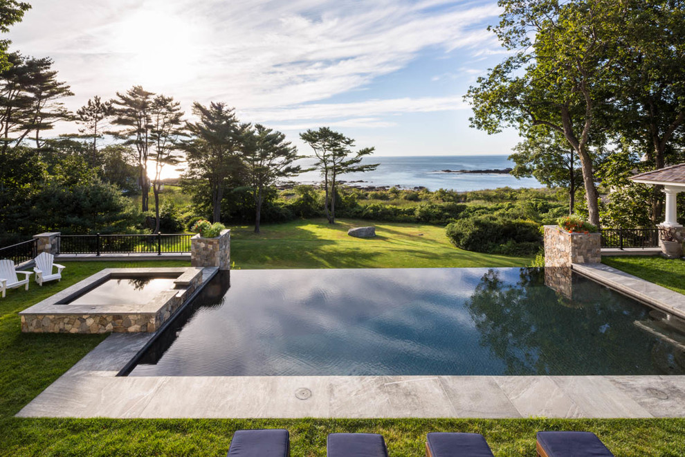 This is an example of an expansive classic back rectangular infinity swimming pool in Boston with a water feature.
