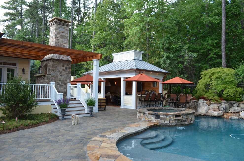 Diseño de piscinas y jacuzzis alargados exóticos de tamaño medio a medida en patio trasero con adoquines de piedra natural