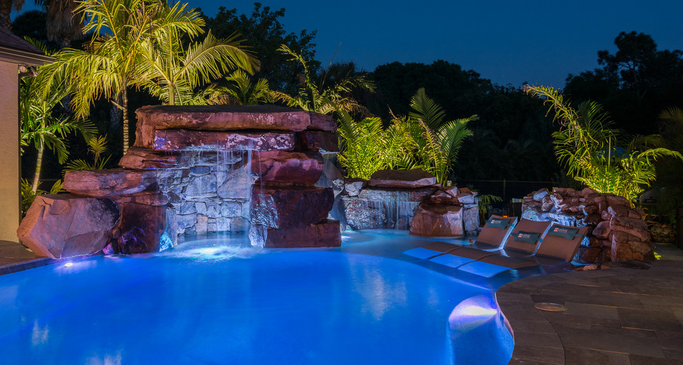 Expansive world-inspired back custom shaped lengths hot tub in Tampa with natural stone paving.