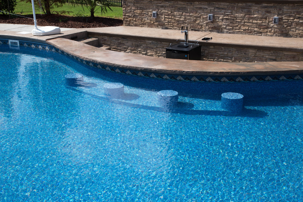 Immagine di una grande piscina personalizzata dietro casa con pavimentazioni in cemento