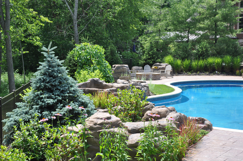 Immagine di una grande piscina naturale chic personalizzata dietro casa con una vasca idromassaggio e pavimentazioni in cemento